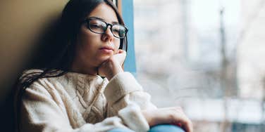 Sad young girl looking out a window.