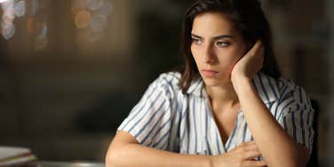 A woman looking contemplative, representing the signs of someone who was chronically invalidated as a child and how it affects them in adulthood