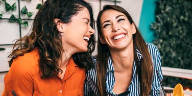 Friends enjoying together in restaurant and looking something at smartphone. 