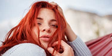 portrait of Red hair woman lying in the hammock in the apple garden against the mountain view. 