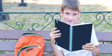 Young boy sitting on a buddy bench at school because he wants to make friends