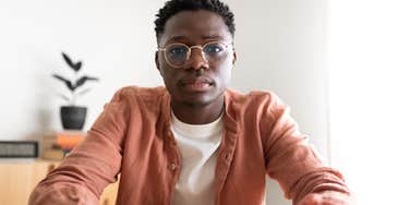 serious young man sitting in home looking at camera