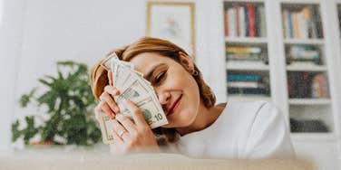 woman holding money showing signs financial growth