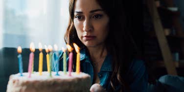 sad woman looking at birthday cake 