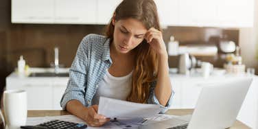 woman looking at bills so she can cancel subscriptions to save money to pay off debt