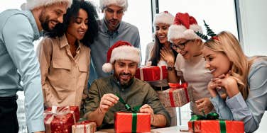 Group of business people in Santa hats, colleagues unpacking gifts at work in the office.