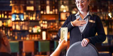 man handing tip to server in restaurant