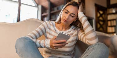 woman looking at iphone with head in hand