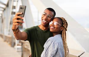 smilng couple taking selfie with phone outdoors