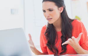 frustrated woman throwing her hands up while looking at computer