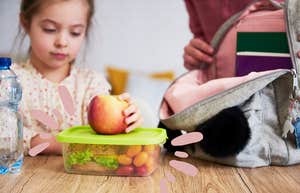 mom helps child pack lunch for school