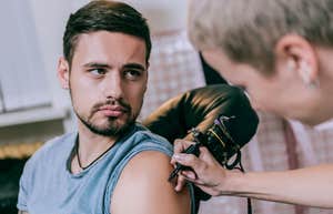 young man gets first tattoo on shoulder