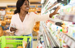 woman reaching for something on a shelf in grocery store