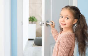 little girl smiling while opening front door