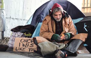 homeless man camped out with tent and sign