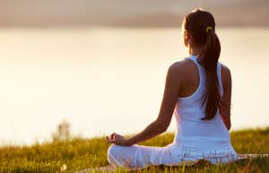 woman meditates by body of water