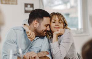 Affectionate woman embracing her husband while sitting at dining table.