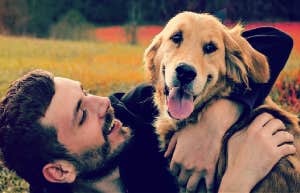 man hugging dog smiling