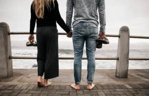 Couple watching turbulent waters, holding hands