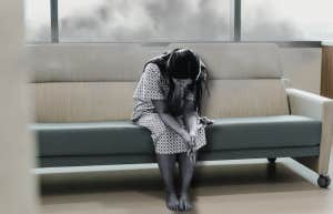 Woman sitting in hospital gown, sad