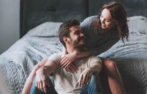 couple sitting in front of bed smiling at each other