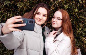 two young girls taking selfie with phone